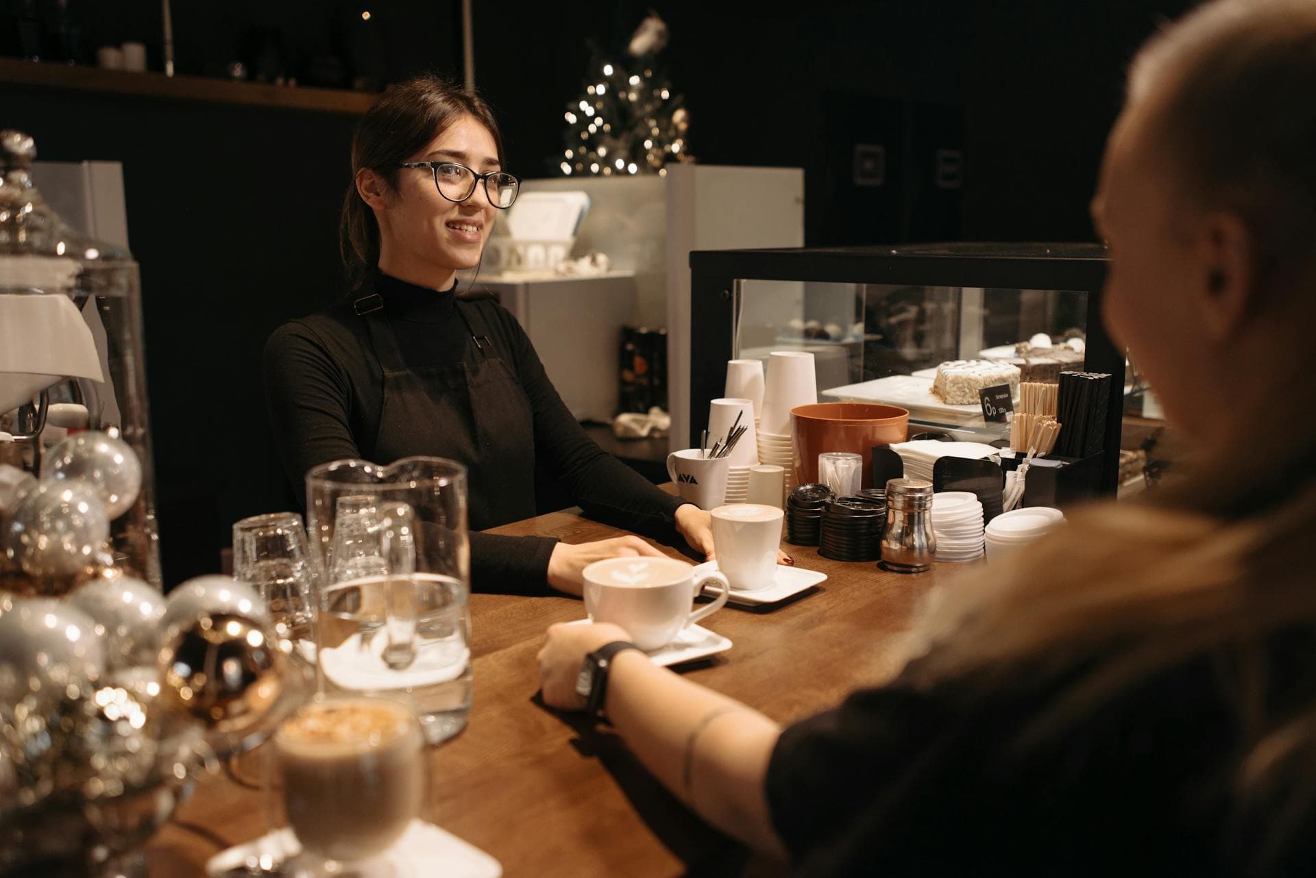 Barista sirviendo café en una cafetería con ambiente acogedor